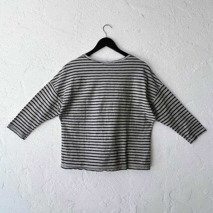 Striped long-sleeve shirt on a hanger against a white wall, viewed from the back