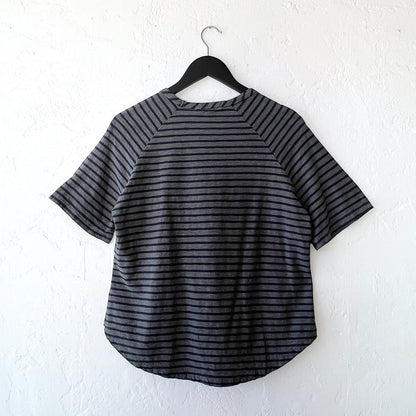 Black and gray striped shirt on a hanger against a white wall as viewed from the back
