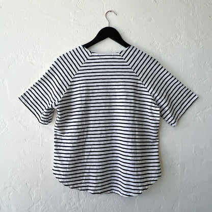 Navy and white striped shirt on a hanger against a white wall