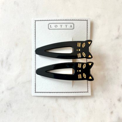 Lotta Cat Duo Clips in Black on their Lotta branded card — two black cellulose acetate snap clips with gold-etched cat-face tops, on a marble surface
