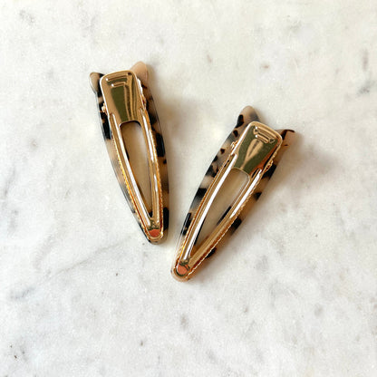 Lotta Cat Duo Clips in Light Tortoise on their Lotta branded card — two cream and black speckled cellulose acetate snap clips with gold-etched cat-face tops, on a marble surface