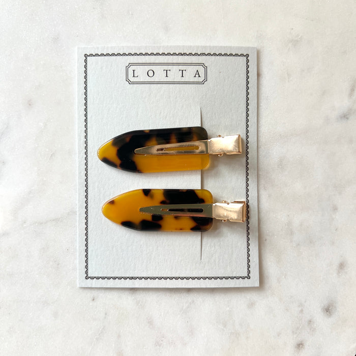 Two tortoiseshell hair clips on a Lotta branded card against a marble background