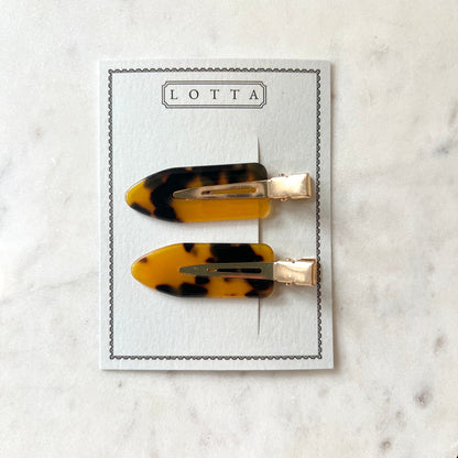 Two tortoiseshell hair clips on a Lotta branded card against a marble background