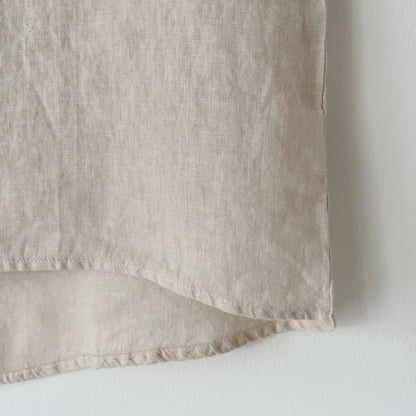 Close-up of the hem of a beige high-low linen tee