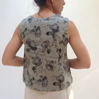 Person wearing a sleeveless top with floral pattern on a plain background, viewed from the back