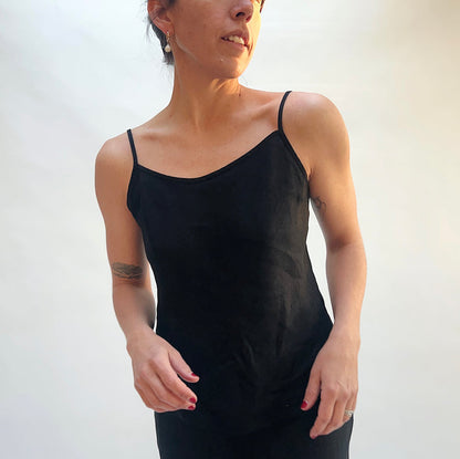 Woman wearing a black tank top against a plain background