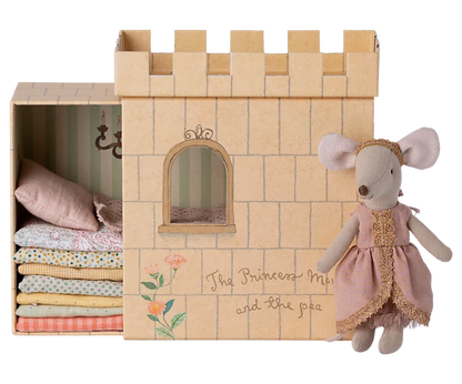 Maileg Princess and the Pea Big Sister Mouse — cotton princess mouse doll in a pink dot dress with gold lace trim and gold headband, standing beside the illustrated castle box with stacked fabric mattresses visible inside