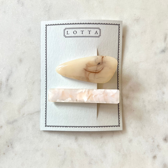Two marble-patterned hair clips on a 'Lotta' branded card against a marble background