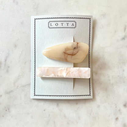 Two marble-patterned hair clips on a 'Lotta' branded card against a marble background