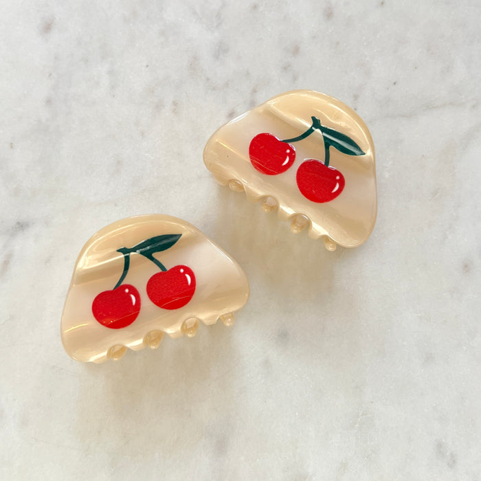 Pair of hair claw clips with cherry design on a marble background