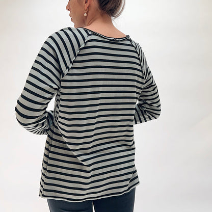 Back view of the Cut Loose Striped Gore Tee in Seal, showing the raglan seam construction, relaxed long-sleeve silhouette, gore panel detailing at the back hem, and raw lettuce-edge finish in seal grey and black horizontal stripe tencel-cotton blend